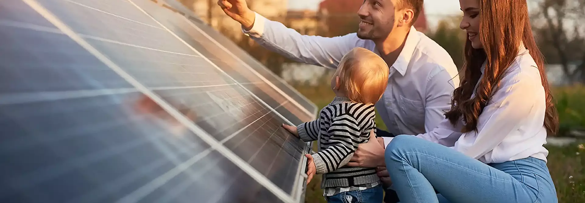 Pai, mãe e bébe na relva a tocarem num painel solar